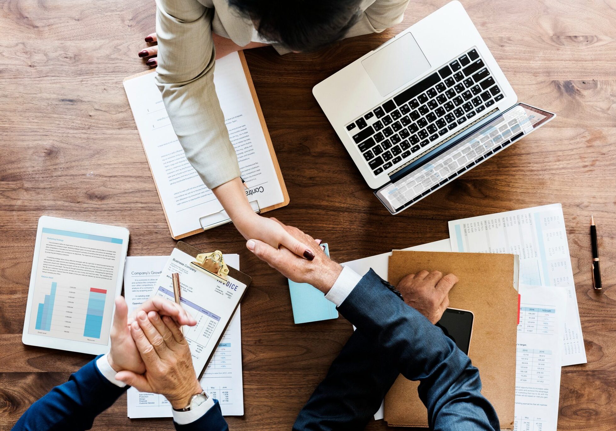 Business people shaking hands over financial paperwork