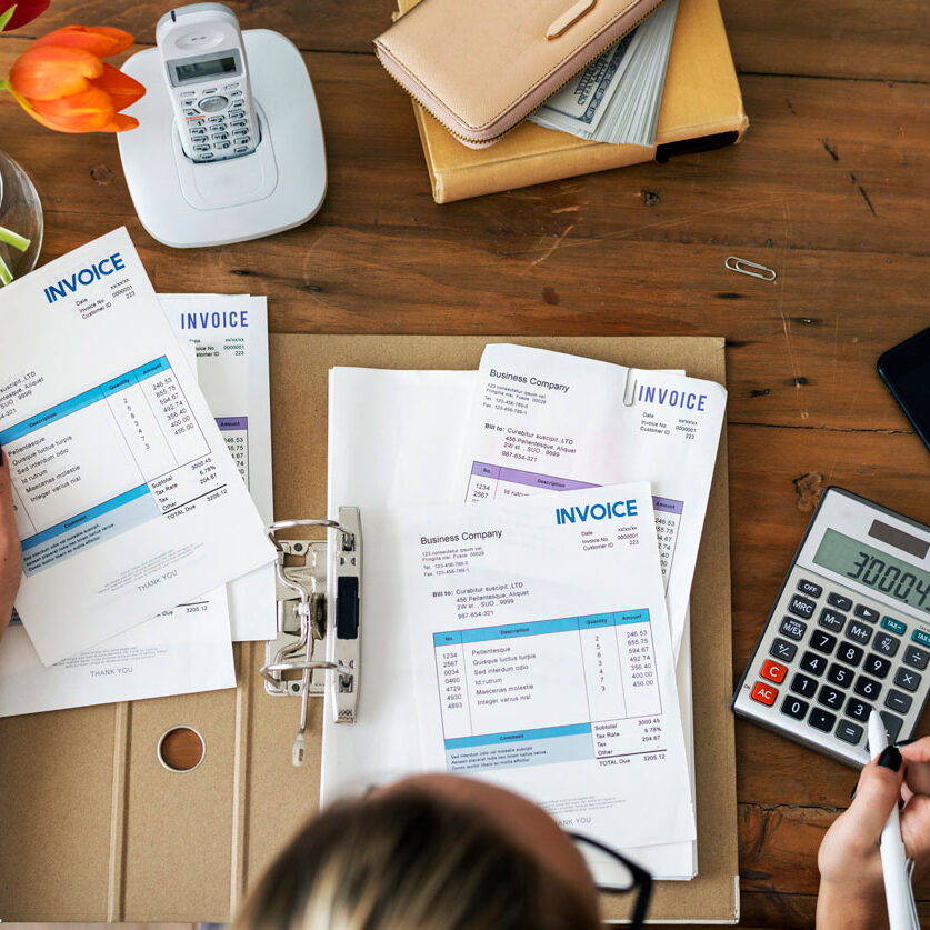hands holding invoices and calculators
